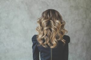 woman in black shirt facing away with brown hair styled using a balayage technique